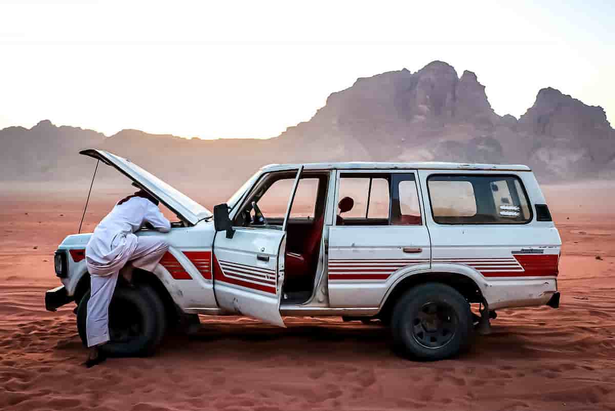 Car with hood raised on the shoulder of a rural desert highway